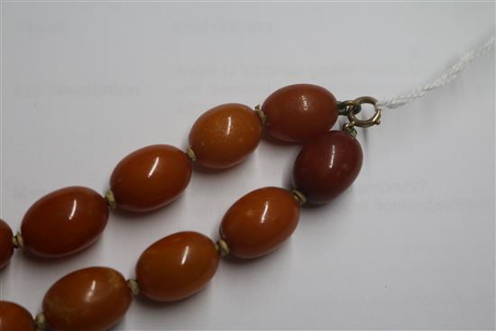 A single strand graduated oval amber bead necklace with 9ct gold clasp, gross weight 62 grams, 60cm.